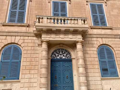 Building with blue shutters and pillars in Pjazza San Pawl in Malta