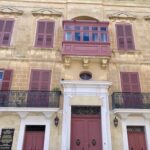 Building with pink shutters and wooden balcony in Pjazza San Pawl in Malta